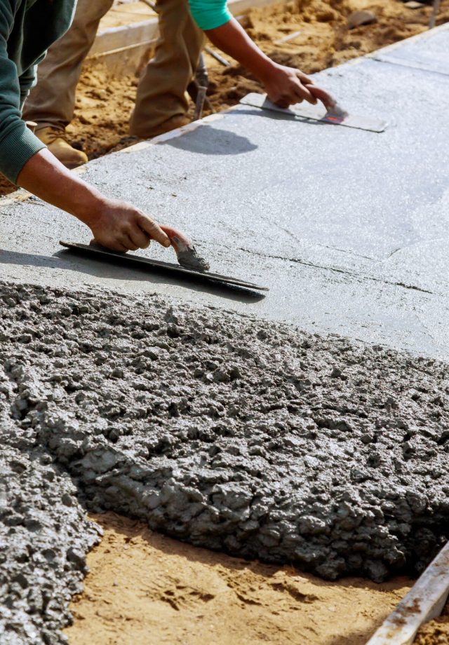 Construction workers laying concrete mixer with concrete mixer in the sidewalk